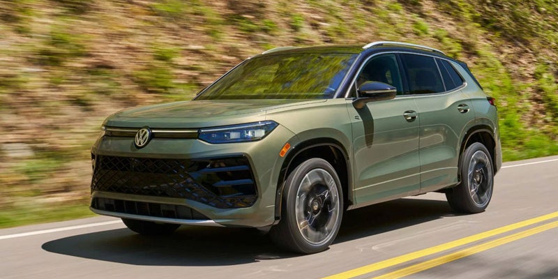 Green Volkswagen Atlas Cross Sport SUV driving on a highway.